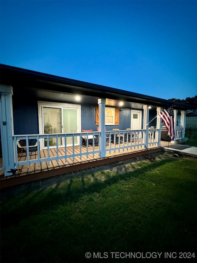 back house at twilight with a yard and a deck