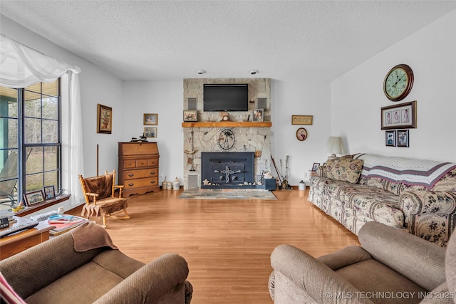 living room with hardwood / wood-style flooring, a textured ceiling, and a fireplace