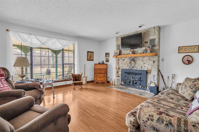 living room with a healthy amount of sunlight, hardwood / wood-style floors, a fireplace, and a textured ceiling