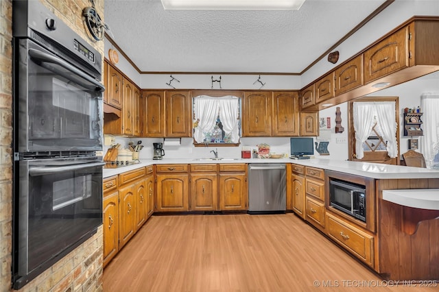 kitchen with stainless steel dishwasher, light hardwood / wood-style flooring, built in microwave, double oven, and a textured ceiling