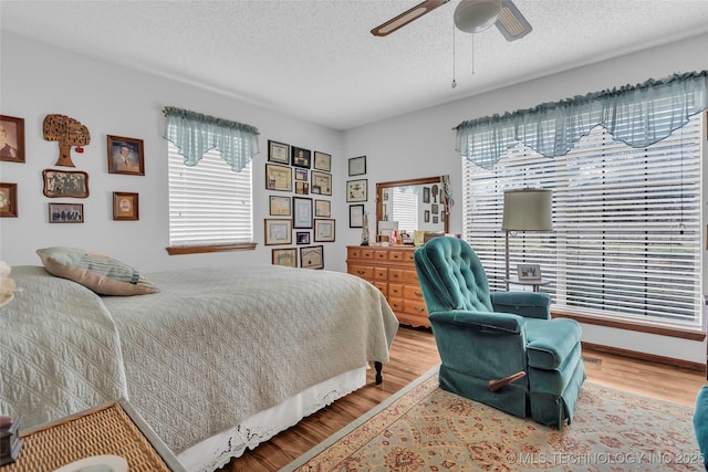 bedroom featuring hardwood / wood-style flooring, a textured ceiling, and ceiling fan