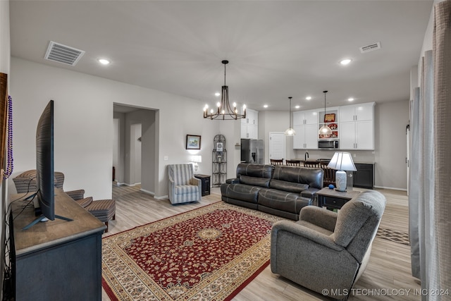 living room featuring light wood-type flooring and a notable chandelier