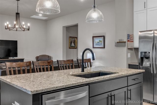 kitchen featuring light stone countertops, stainless steel appliances, sink, and a center island with sink