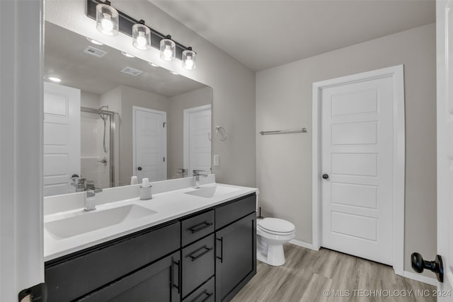 bathroom with vanity, toilet, wood-type flooring, and a shower with shower door