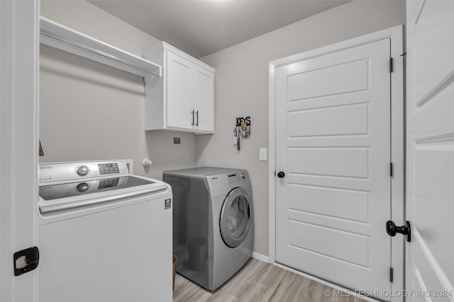 washroom featuring light hardwood / wood-style floors, cabinets, and separate washer and dryer