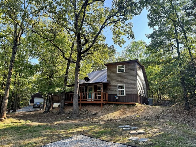 back of property featuring a wooden deck, central air condition unit, and a garage