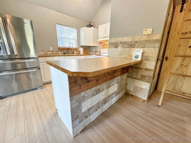 kitchen with light hardwood / wood-style floors, lofted ceiling, white stove, and stainless steel refrigerator