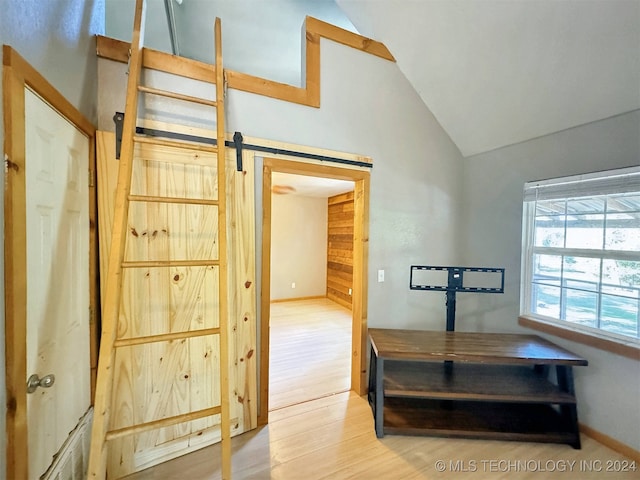 hall featuring lofted ceiling, hardwood / wood-style floors, and a barn door