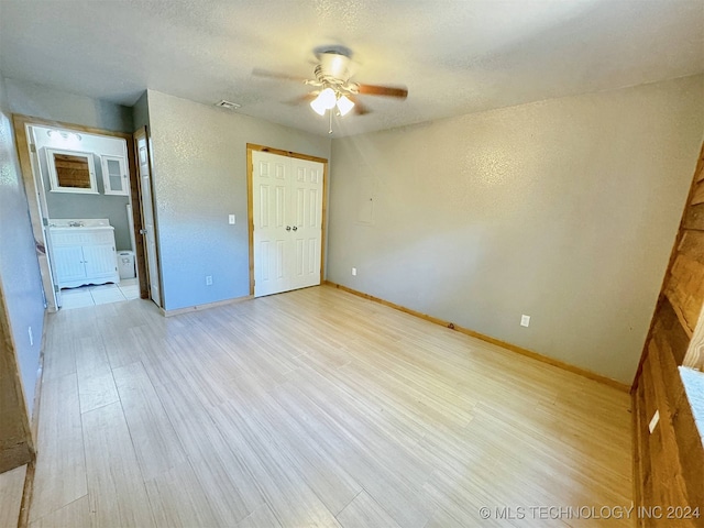 empty room featuring light hardwood / wood-style flooring, a textured ceiling, and ceiling fan