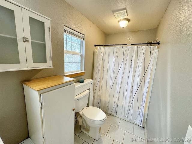 bathroom with toilet, a textured ceiling, curtained shower, and tile patterned floors