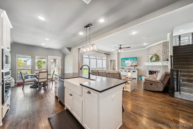 kitchen featuring sink, stainless steel appliances, a fireplace, white cabinets, and a center island with sink