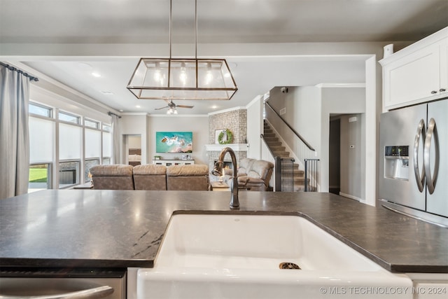 kitchen featuring crown molding, sink, stainless steel fridge with ice dispenser, and decorative light fixtures