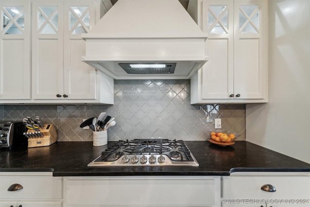 kitchen featuring decorative backsplash, stainless steel gas stovetop, white cabinets, and premium range hood