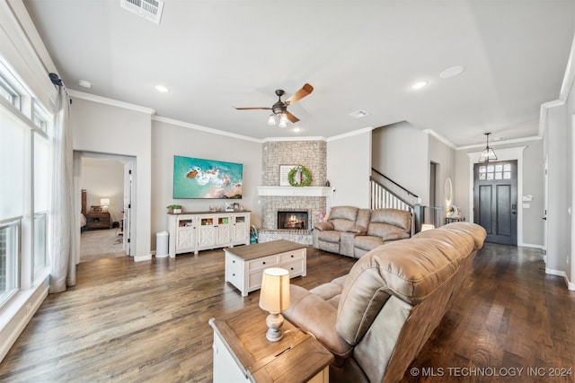 living room featuring ceiling fan, dark hardwood / wood-style floors, crown molding, and a fireplace