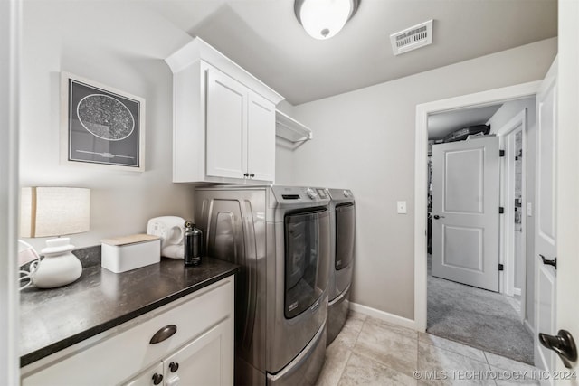 laundry room featuring cabinets, light tile patterned floors, and independent washer and dryer