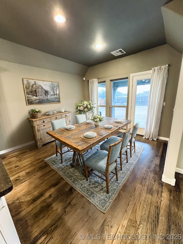 dining space with lofted ceiling and dark wood-type flooring