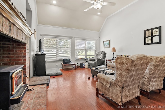 living room with ceiling fan, high vaulted ceiling, wood-type flooring, crown molding, and a wood stove