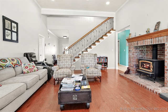 living room featuring a wood stove, hardwood / wood-style flooring, a high ceiling, and crown molding