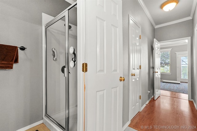 bathroom with a shower with door, crown molding, and wood-type flooring