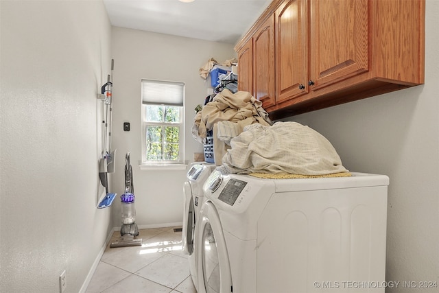 laundry room with light tile patterned floors, cabinets, and washer and clothes dryer