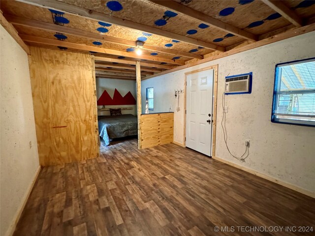 spare room with beamed ceiling, a wall unit AC, and dark hardwood / wood-style floors