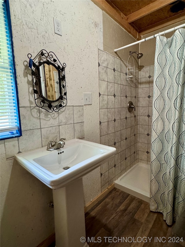 bathroom with tile walls, hardwood / wood-style flooring, curtained shower, and sink