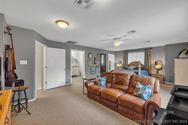 bedroom with light carpet, ensuite bath, and ceiling fan