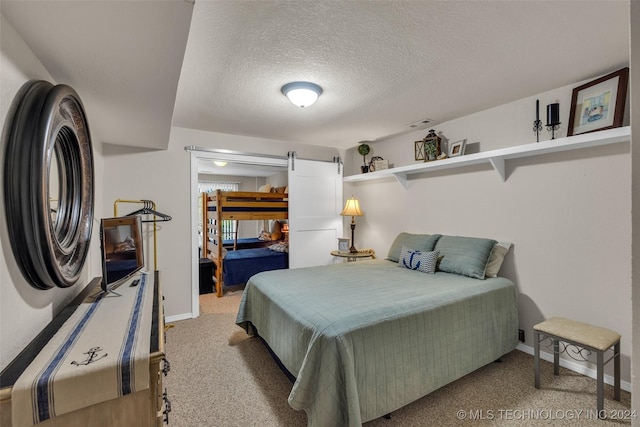 bedroom with light carpet, a textured ceiling, and a barn door