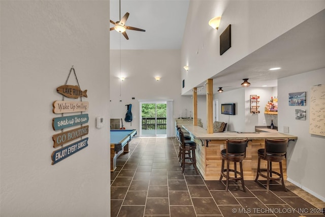 kitchen with ceiling fan, a towering ceiling, pool table, kitchen peninsula, and a breakfast bar area