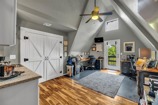 office space featuring ceiling fan, sink, lofted ceiling, and light wood-type flooring