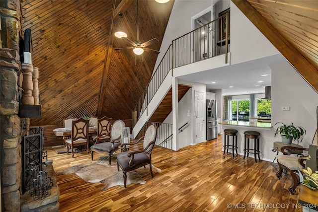 living area featuring wood-type flooring, high vaulted ceiling, ceiling fan, and wood ceiling