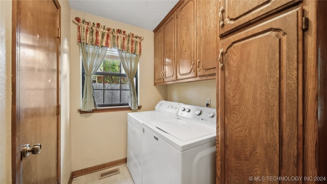 laundry room featuring cabinets, a textured ceiling, washing machine and dryer, and light tile patterned flooring