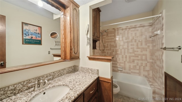 full bathroom featuring vanity, tiled shower / bath combo, and toilet