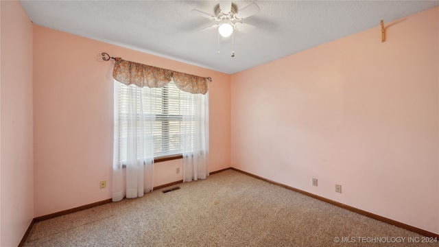 carpeted empty room with ceiling fan and a textured ceiling