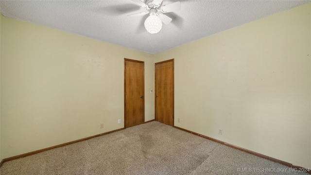 carpeted spare room featuring ceiling fan and a textured ceiling