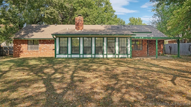 back of property with a yard and a sunroom