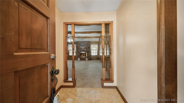 foyer entrance with a brick fireplace, light carpet, and a textured ceiling