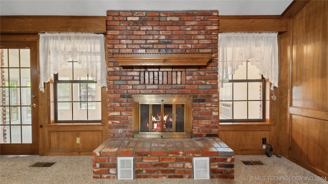 unfurnished living room featuring a textured ceiling, wooden walls, a fireplace, and carpet flooring