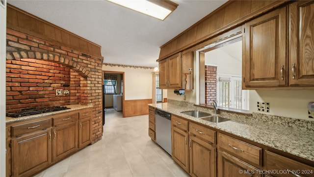 kitchen featuring wood walls, sink, a textured ceiling, stainless steel appliances, and light stone countertops