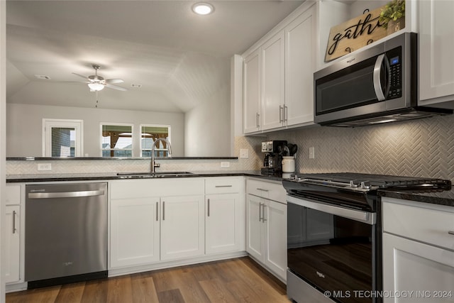 kitchen with backsplash, lofted ceiling, stainless steel appliances, and white cabinets