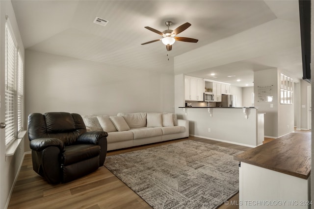 living room with ceiling fan, lofted ceiling, wood-type flooring, and a healthy amount of sunlight