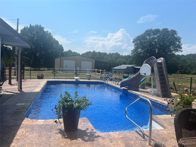 view of pool with a water slide, a garage, and an outdoor structure