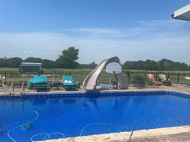 view of pool with a water slide and a patio area