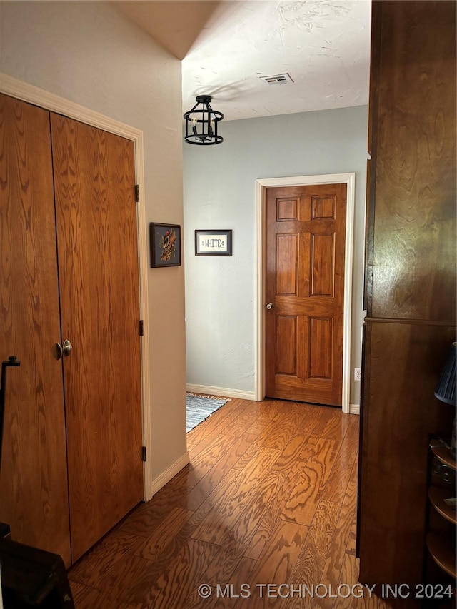 corridor featuring hardwood / wood-style floors and an inviting chandelier