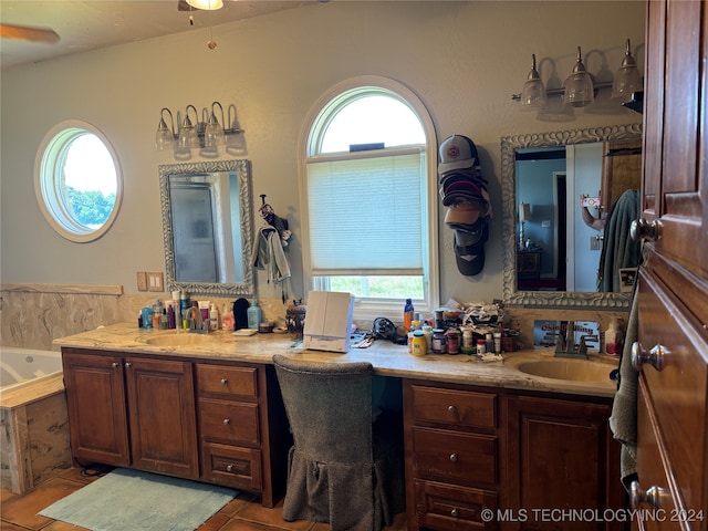 bathroom with vanity, ceiling fan, a healthy amount of sunlight, and tiled tub