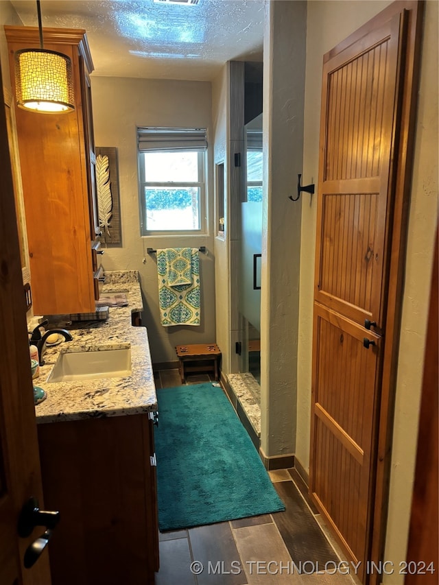 bathroom featuring vanity, a textured ceiling, wood-type flooring, and walk in shower