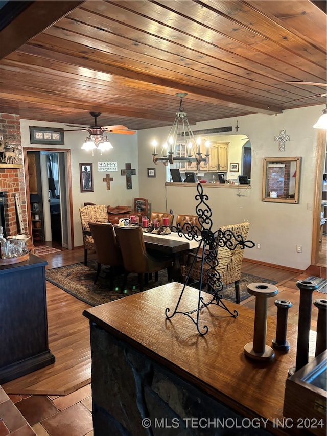 dining space featuring ceiling fan with notable chandelier, wood ceiling, a fireplace, and light hardwood / wood-style floors