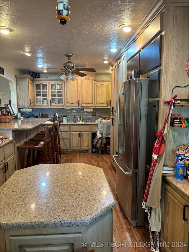 kitchen featuring ceiling fan, dark hardwood / wood-style floors, a kitchen island, and stainless steel fridge