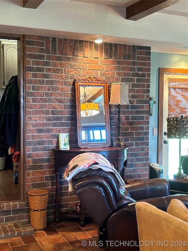 living room featuring brick wall and beamed ceiling