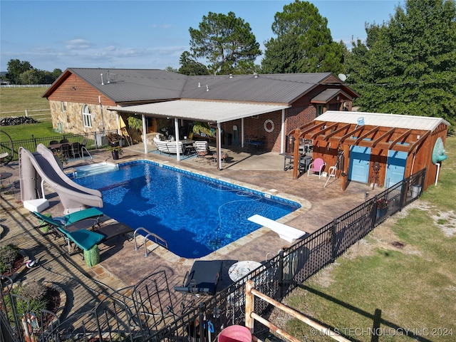 view of pool featuring a patio area, a water slide, a yard, and a diving board